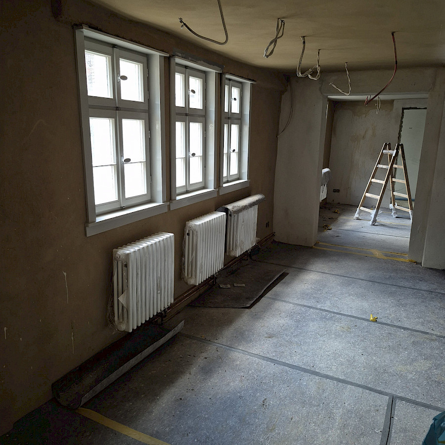 Blick in renovierte Räume mit Haupthaus mit neuen Heizungen an den Wänden und Kabeln, die von der Decke hängen
